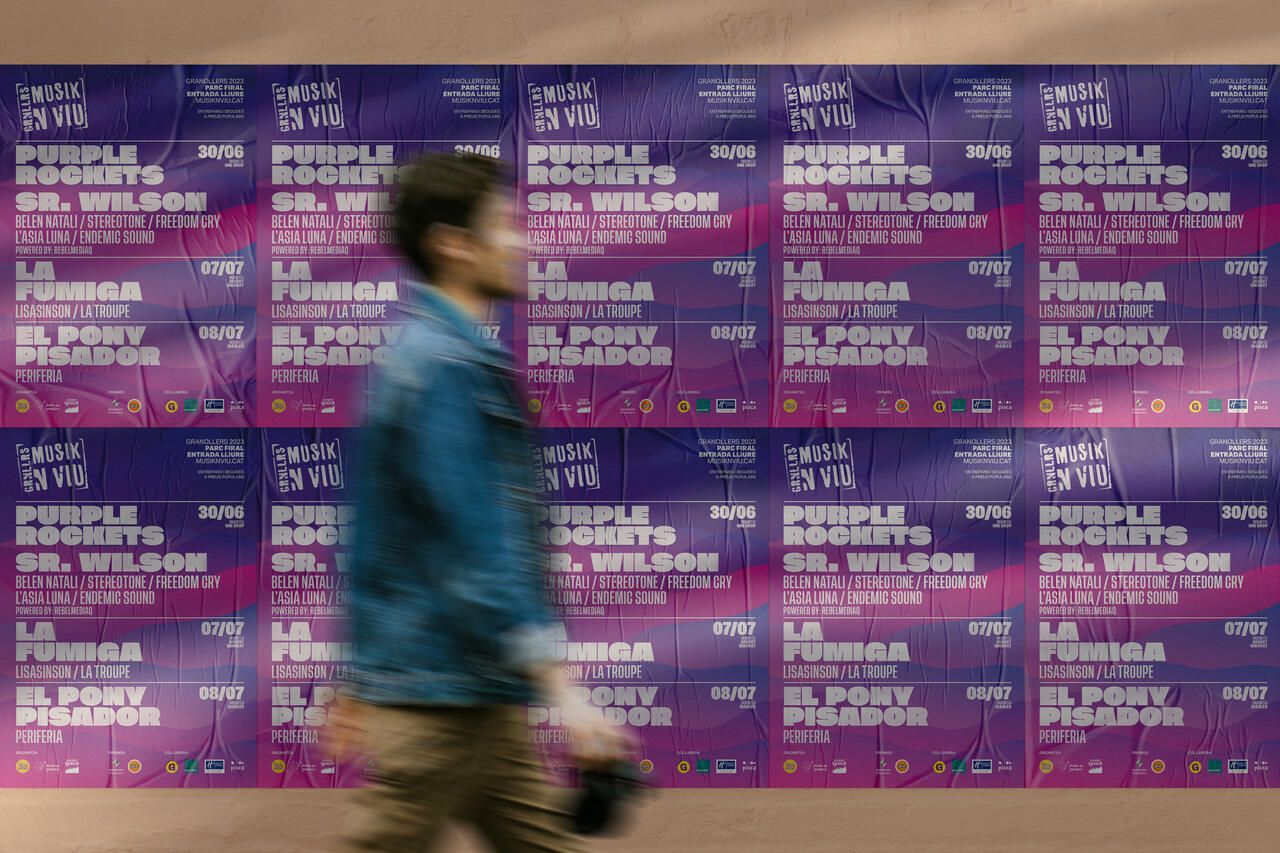 Wall of Musik'n'viu posters pasted in a row on the street, with the wave system and the line-up for all three nights