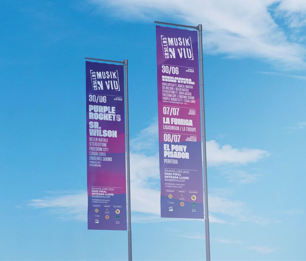 Musik'n'viu festival street banners flying against the sky, with the visual identity and each night's programme